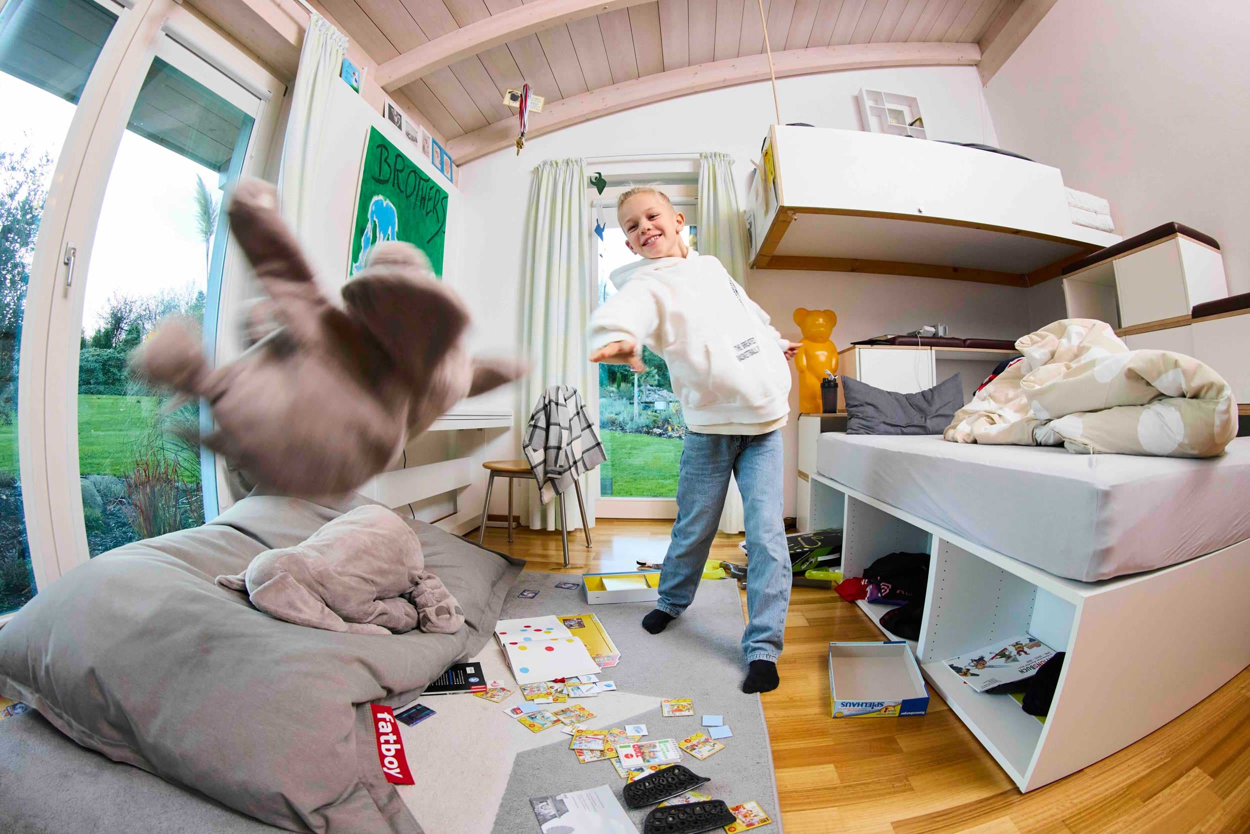 Junge im Zimmer wirft ein Kuscheltier